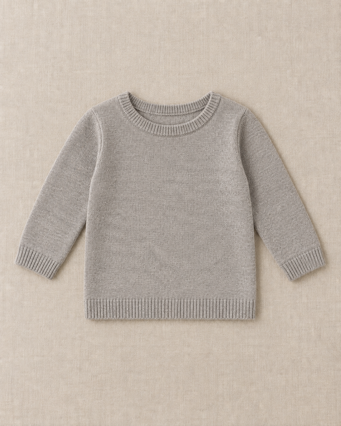 Grey fine gauge knit pullover with long sleeves, a ribbed crew neck, ribbed cuffs and a ribbed straight hem, laid flat on a linen surface.