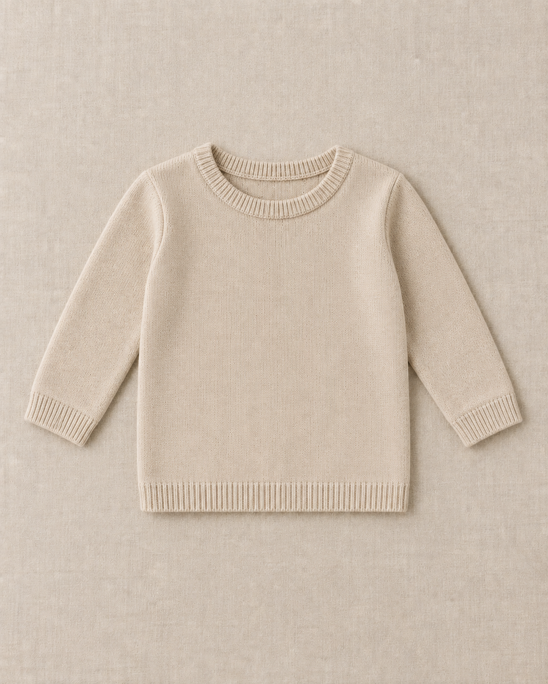Sand fine gauge knit pullover with long sleeves, a ribbed crew neck, ribbed cuffs and a ribbed straight hem, laid flat on a linen surface.